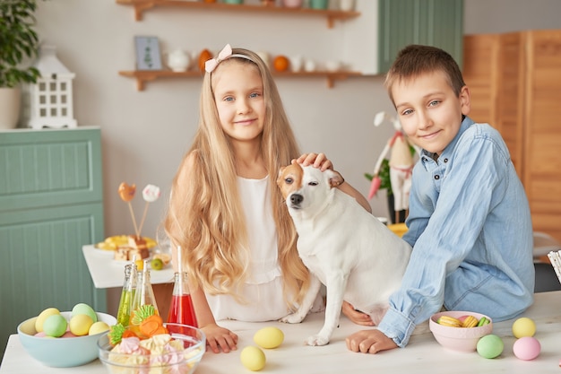 Bambini che giocano con il loro cane su un tavolo decorato a Pasqua