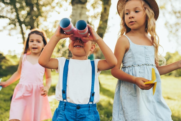 Bambini che giocano con un binocolo e un aeroplano di carta in una giornata estiva nel parco Bambini felici che giocano a finta safari all'aperto nella foresta Concetto di infanzia