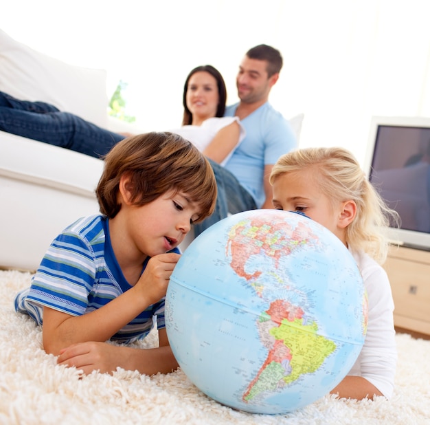 Bambini che giocano con un globo terrestre nel soggiorno