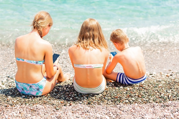 Bambini che giocano e cercano il web sui telefoni in spiaggia