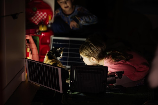 Bambini che giocano in casa durante un blackout utilizzando illuminazione alternativa con pannello solare