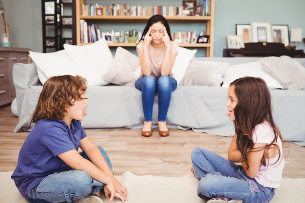 Bambini che giocano mentre madre seduta sul divano