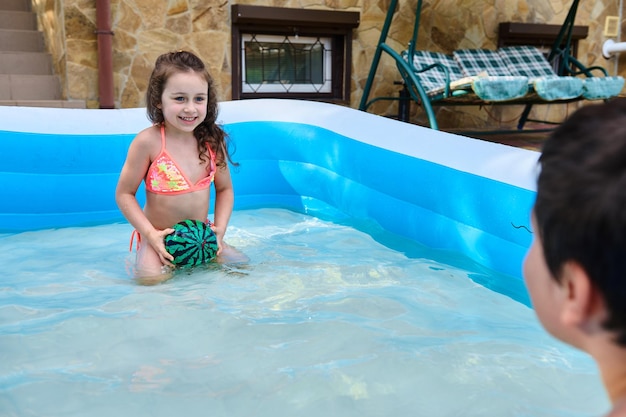 Bambini che giocano nella piscina gonfiabile Fratelli che si divertono in piscina Vacanze estive e concetto di vacanza