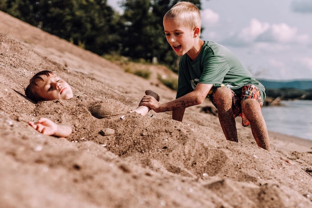 Bambini che giocano sulla sabbia sulla spiaggia contro il cielo