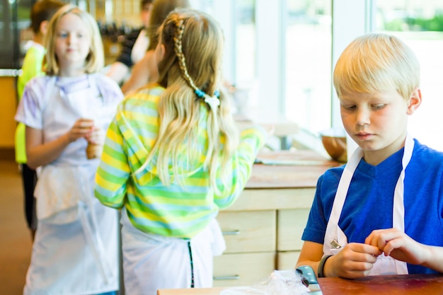 Bambini che imparano a cucinare in un corso di cucina.