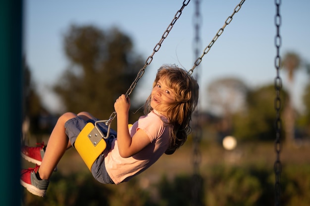 Bambini che oscillano nel parco giochi carino ragazzino divertente mentre giocano nel parco giochi estivo