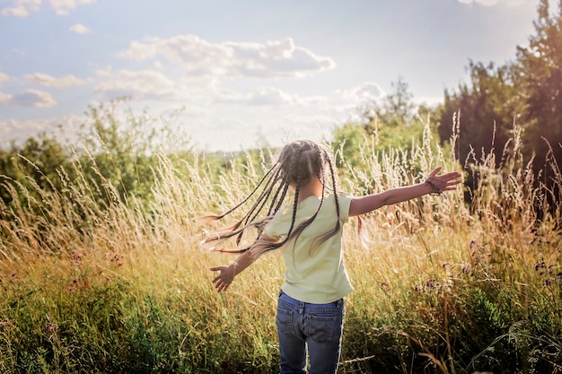 Bambini che si divertono nell'erba verde con i fiori sul prato, tramonto dorato in estate