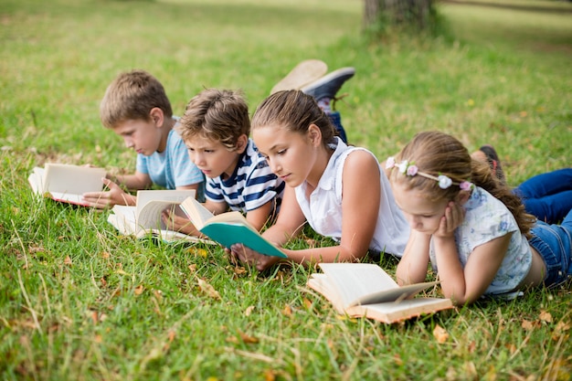 Bambini che si trovano sull'erba e libri di lettura