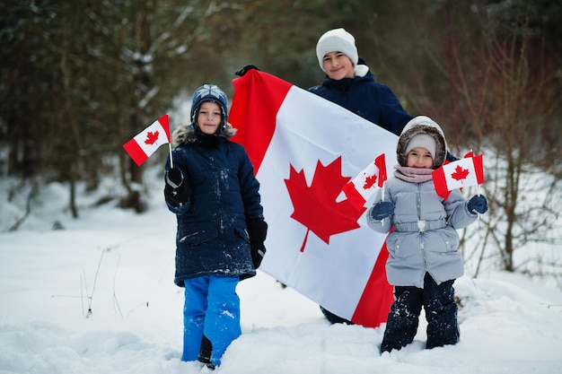 Bambini che tengono bandiera del Canada sul paesaggio invernale.