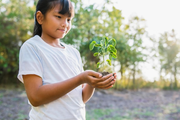 Bambini che tengono piccolo albero per piantare il concetto di giornata della terra