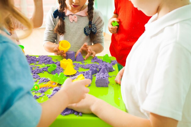 Bambini che usano forme di plastica per giocare con la sabbia cinetica all'asilo