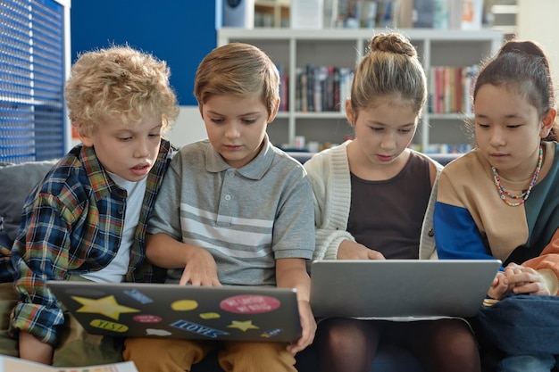 Bambini che usano i computer nella biblioteca scolastica