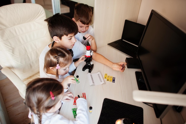Bambini che usano il microscopio imparano la lezione di scienze a casa.