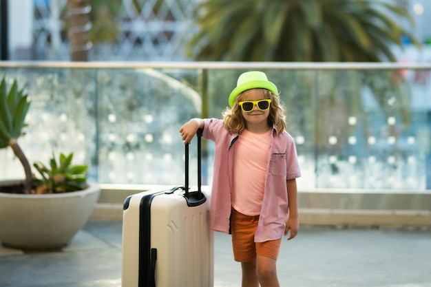 Bambini che viaggiano bambino turista viaggiatore in abiti casual moda occhiali da sole e cappello tenere la valigia