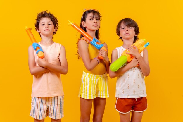 Bambini con pistole ad acqua su sfondo giallo vacanze estive