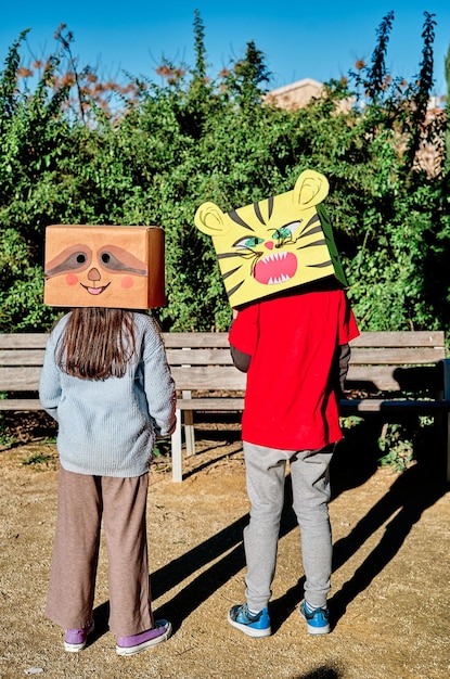 Bambini con teste in scatola di cartone che giocano nel parco