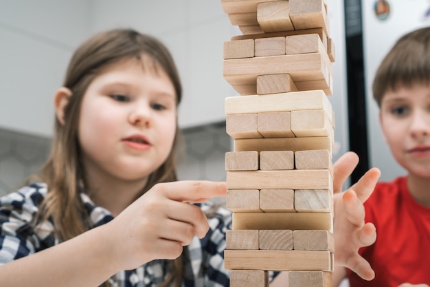 Bambini concentrati e appassionati che giocano insieme a un gioco da tavolo di equilibrio gioco di torri di mattoni in legno Comanda la battaglia dei bambini