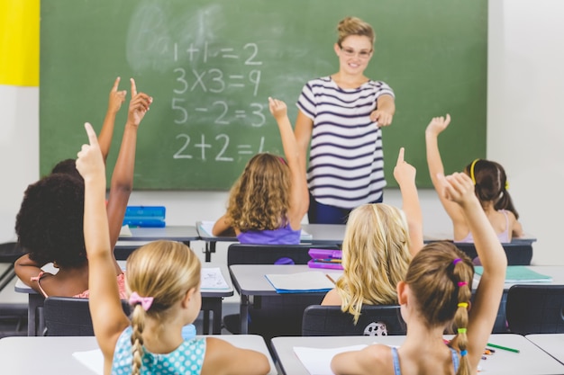 Bambini della scuola che sollevano la mano in aula