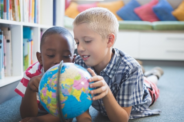 Bambini della scuola che studiano globo in biblioteca