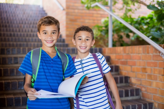 Bambini della scuola che tengono un libro sulla scala