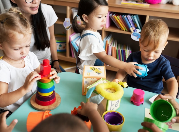 Bambini della scuola materna che giocano con l&#39;insegnante nell&#39;aula