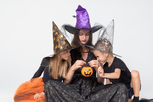 Bambini di Halloween Una famiglia felice madre e bambini in costumi e cappelli da strega inquietanti guardano in un cesto