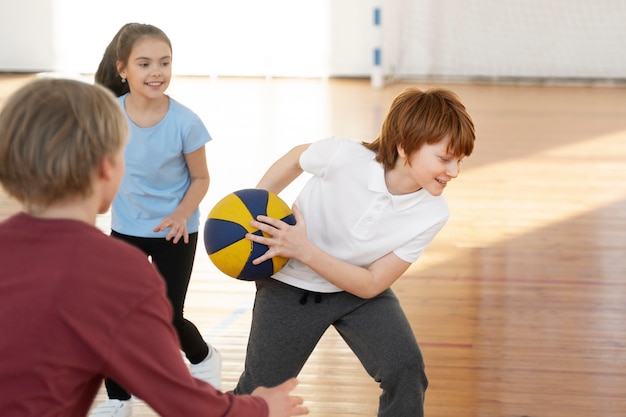 Bambini di tiro medio che giocano a basket insieme