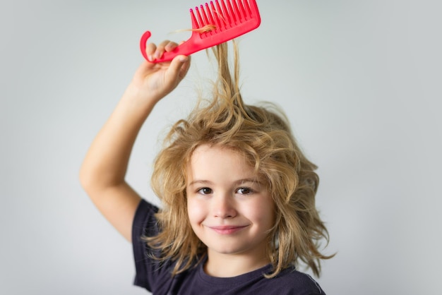 Bambini divertenti acconciatura bambino con i capelli lunghi biondi aggrovigliati cerca di pettinarlo capelli ritratto capretto con ac