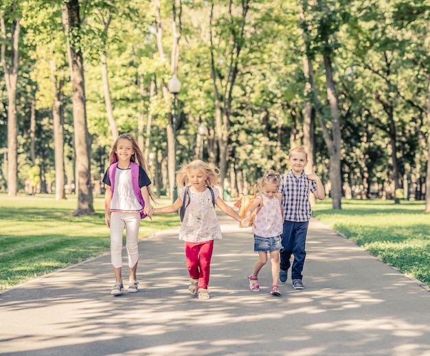 Bambini divertenti che si tengono per mano e camminano insieme nel parco