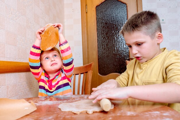 Bambini divertenti cuociono i biscotti in cucina. famiglia felice.