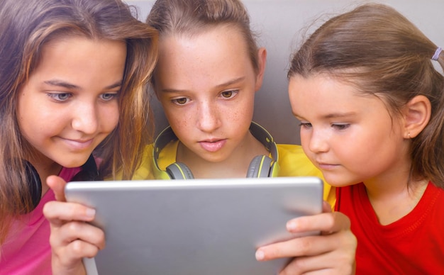 Bambini e adolescenti guardano insieme lo stesso tablet sullo stesso divano