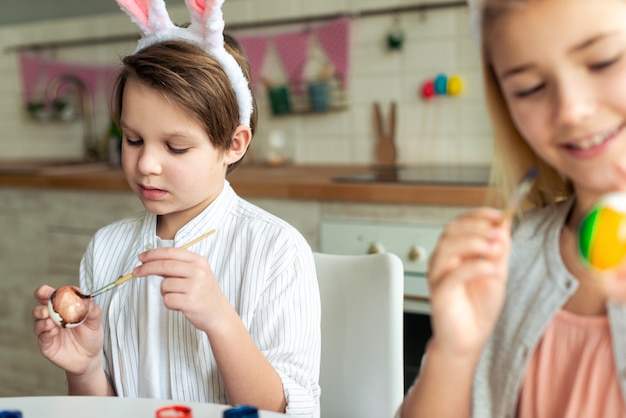 Bambini felici che colorano le uova di Pasqua, preparando il cestino di Pasqua