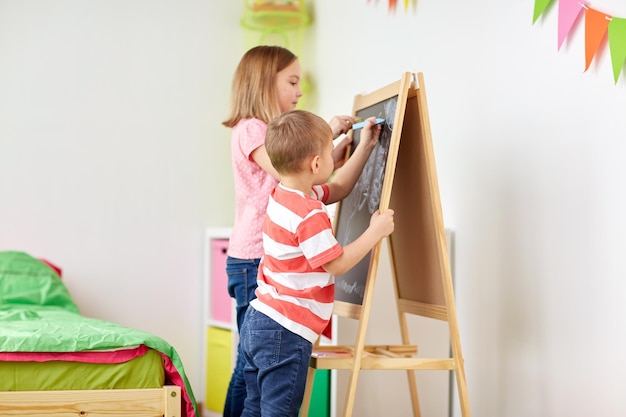 bambini felici che disegnano sulla tavola di gesso a casa