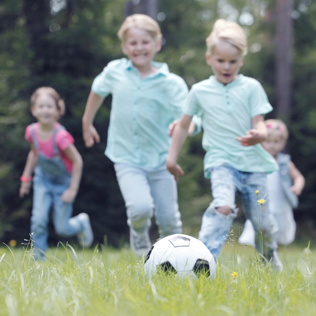 Bambini felici che giocano a calcio nel parco estivo