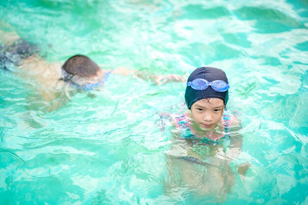 Bambini felici che giocano a nuotare in piscina