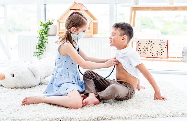 Bambini felici che giocano al dottore nella stanza leggera