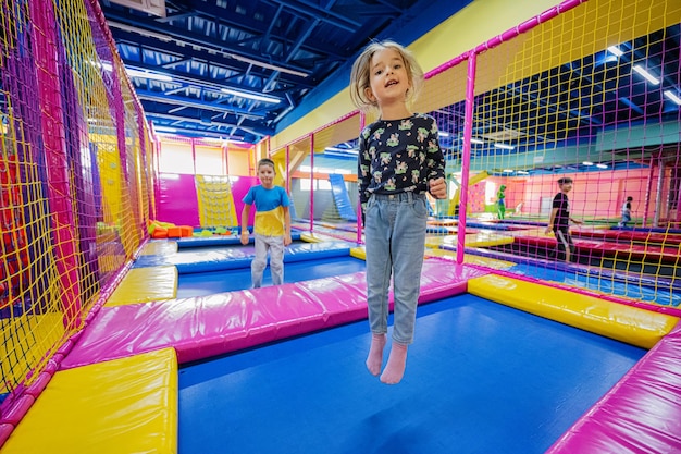 Bambini felici che giocano al parco giochi del centro giochi al coperto Ragazza che salta sul trampolino