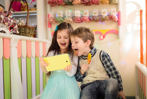 Bambini felici che giocano tablet nel negozio di dolciumi