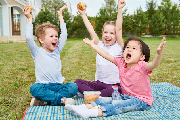 Bambini felici che godono del picnic sul prato inglese