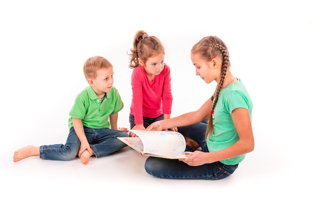 Bambini felici che leggono un libro isolato su bianco. Lavoro di squadra, concetto di creatività.