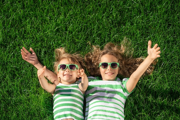 Bambini felici che pongono sull'erba verde. Bambini divertenti all'aperto nel giardino di primavera.