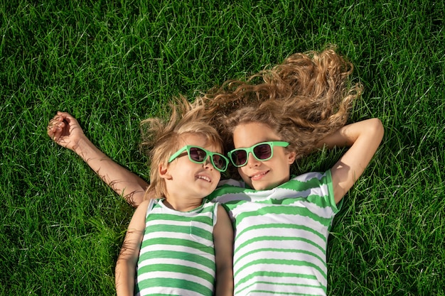 Bambini felici che pongono sull'erba verde. Bambini divertenti all'aperto nel giardino di primavera.