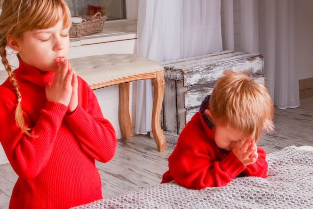 Bambini felici che pregano a casa per Natale