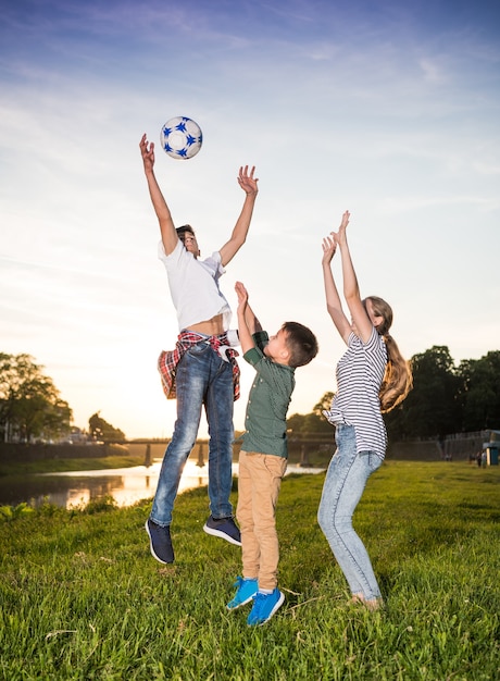 Bambini felici che saltano e giocano con la palla all'aperto. Giornata di sole estivo