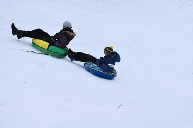 Bambini felici che scendono dallo scivolo di neve in inverno. ricreazione invernale di sport attivi per bambini allegri. sci alpino sul ghiaccio