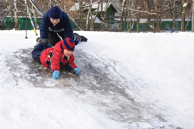 Bambini felici che scivolano da una piccola collina innevata. Bambino in inverno