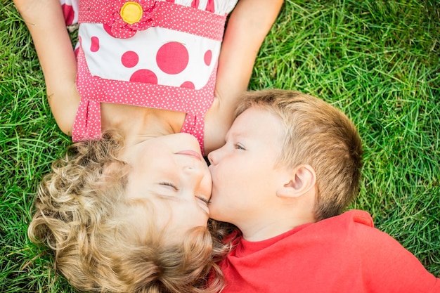 Bambini felici che si divertono all'aperto Bambini che giocano nel parco primaverile Ragazzo e ragazza sdraiati sull'erba verde