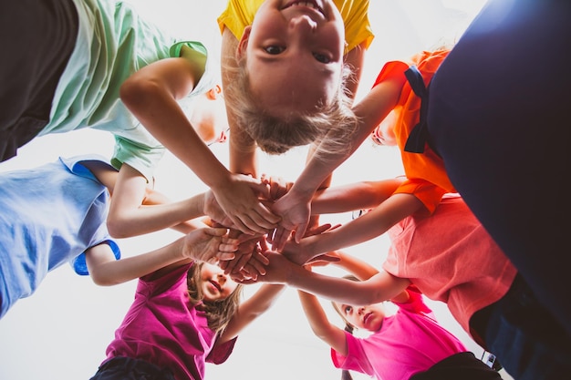 Bambini felici che uniscono le mani all'aperto Estate all'aperto giochi e tempo libero Lavoro di squadra e concetto di amicizia