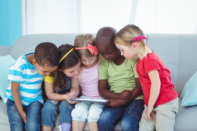 Bambini felici che utilizzano tecnologia stando seduti