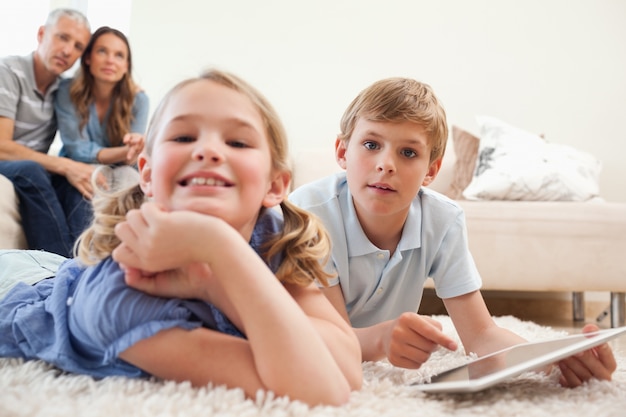 Bambini felici che utilizzano un tablet PC con i loro genitori sul